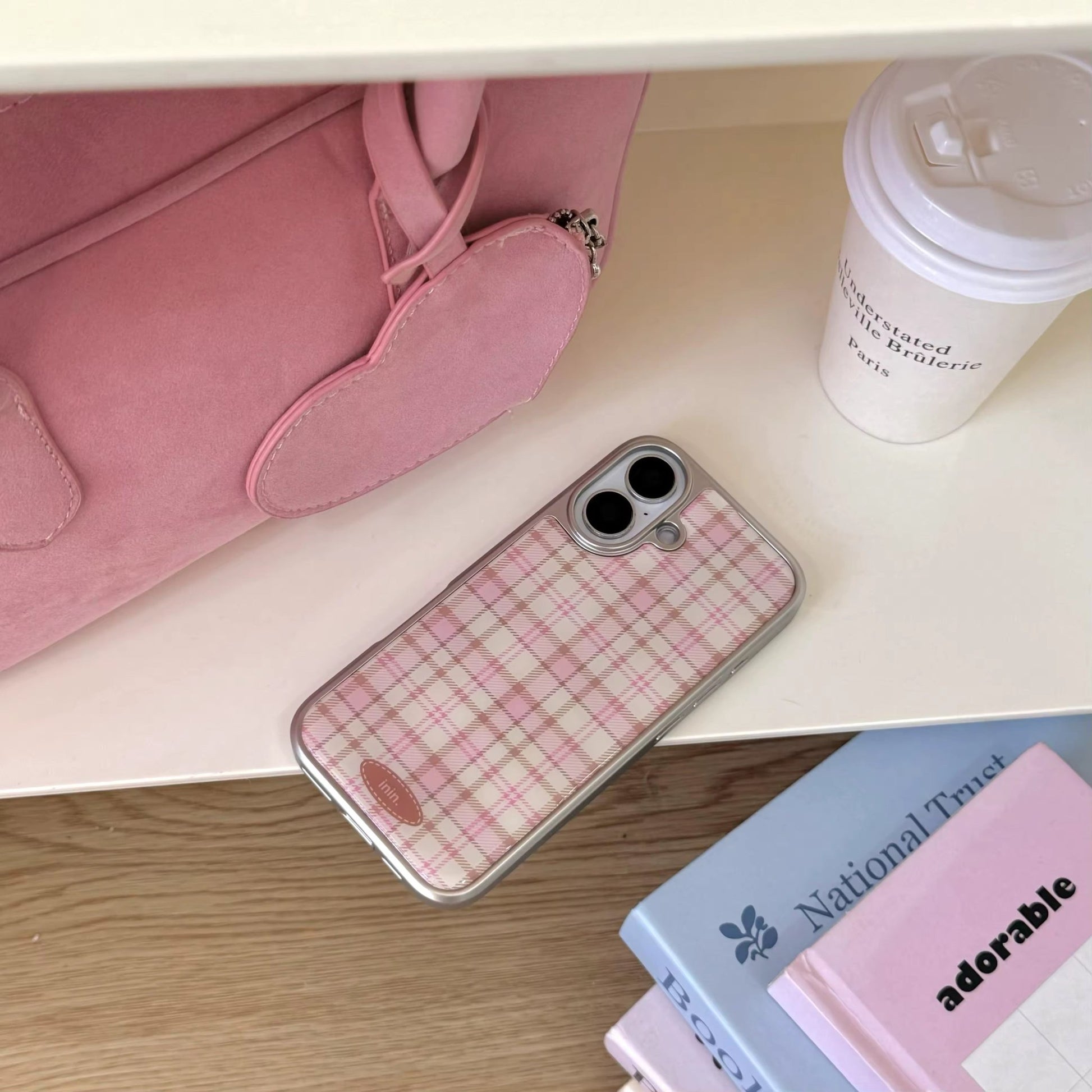 Pink aesthetic phone case lying next to pastel books and a latte cup for cozy desk setup