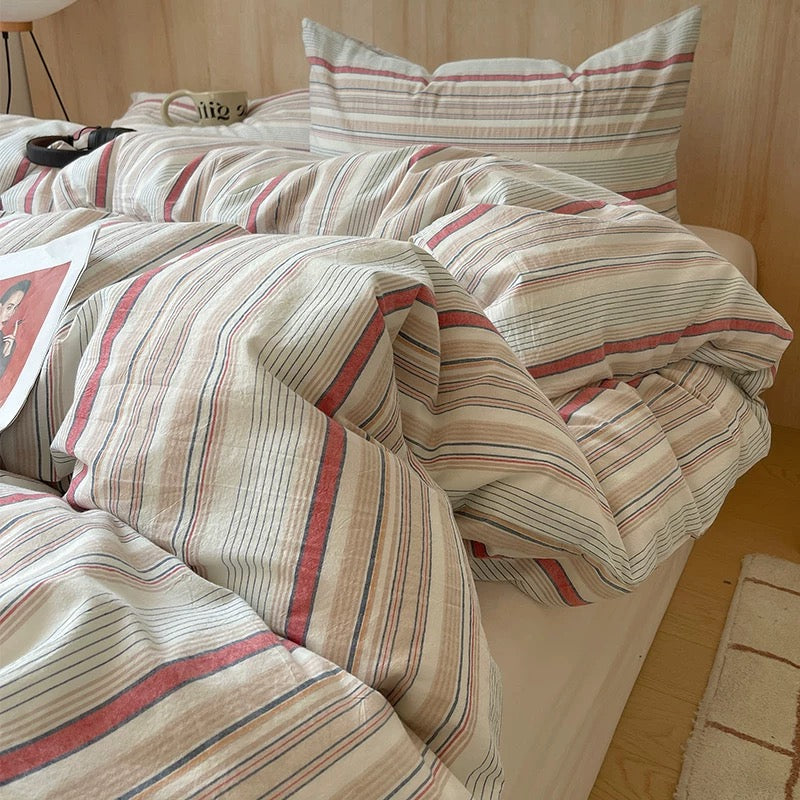 Striped bedding set on a bed with pillows in a bedroom setting.
