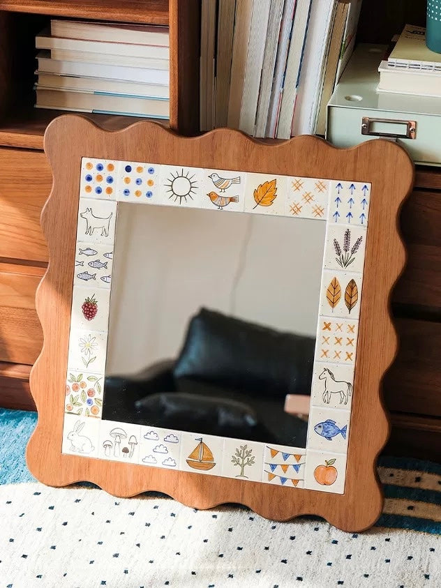 A scalloped wall mirror with a brown frame leans beside shelves, reflecting dark furniture in its glass center.