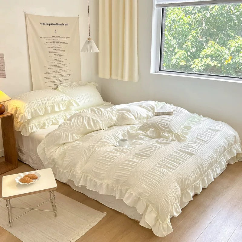 Neatly made bed with white bedding in a bright room with a window and side table.