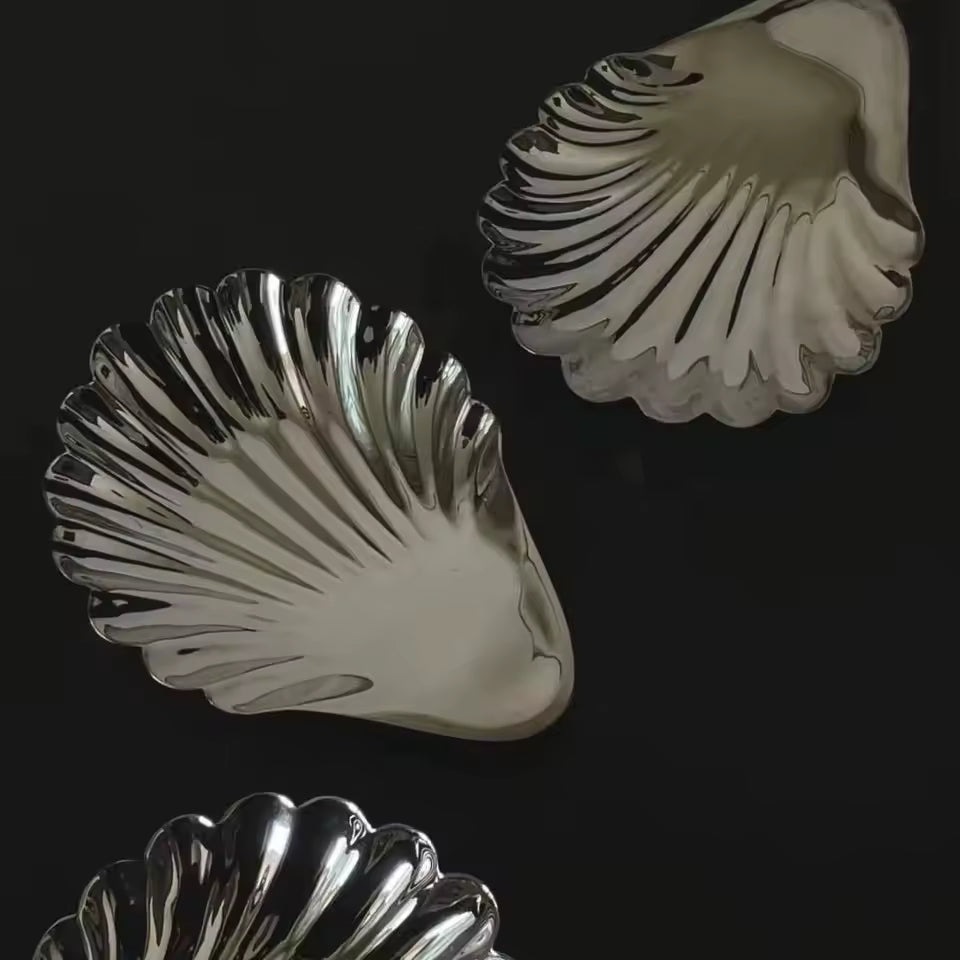 Three silver shell-shaped dishes on a black background