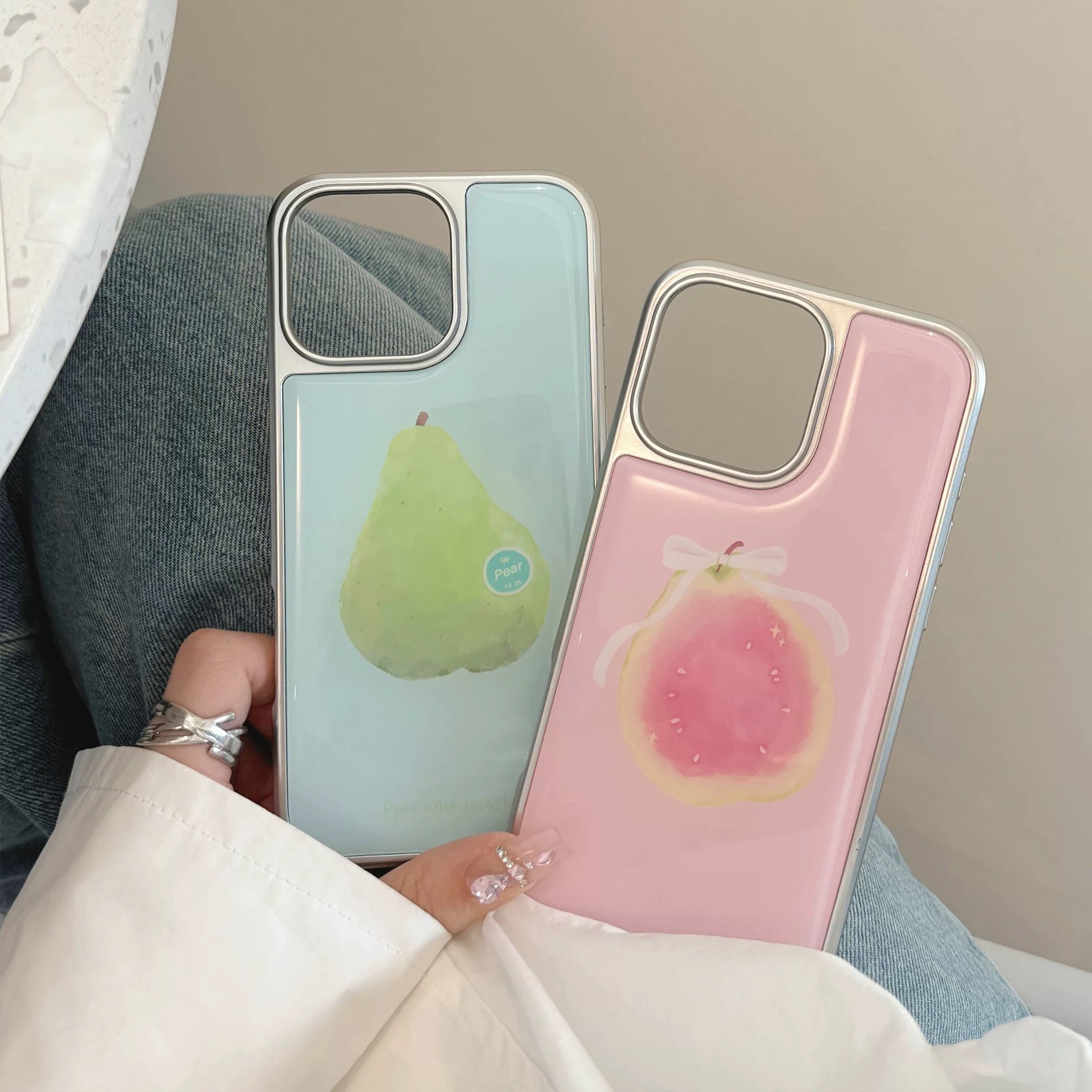 Three pastel fruit iPhone cases — apple, pear, guava — laid out on a neutral table, styled for aesthetic Instagram feed.