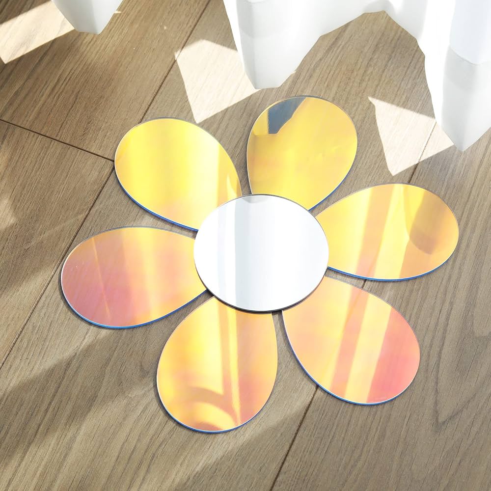 A flower-shaped floor mirror with six reflective petals and a round silver center, placed on a wooden floor near white curtains.