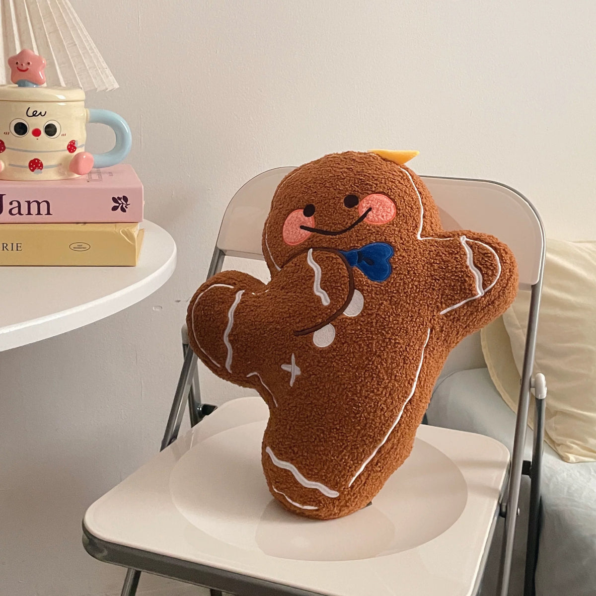 Smiling gingerbread man pillow with blue bow tie and white icing details on a chair