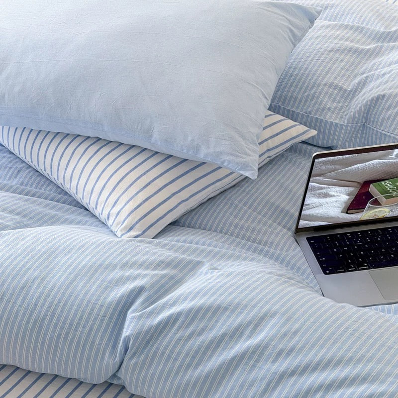 Japandi inspired blue striped bedding layered naturally with neutral decor creating relaxing everyday sleep environment indoors today.