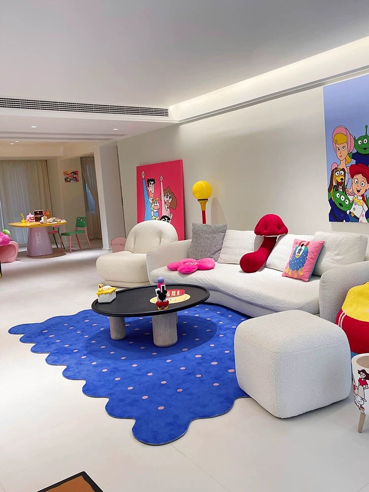 Modern living room with a blue abstract rug, white sofa, and colorful decor.