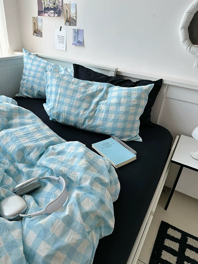 Bed with blue checkered bedding and pillows in a room setting.