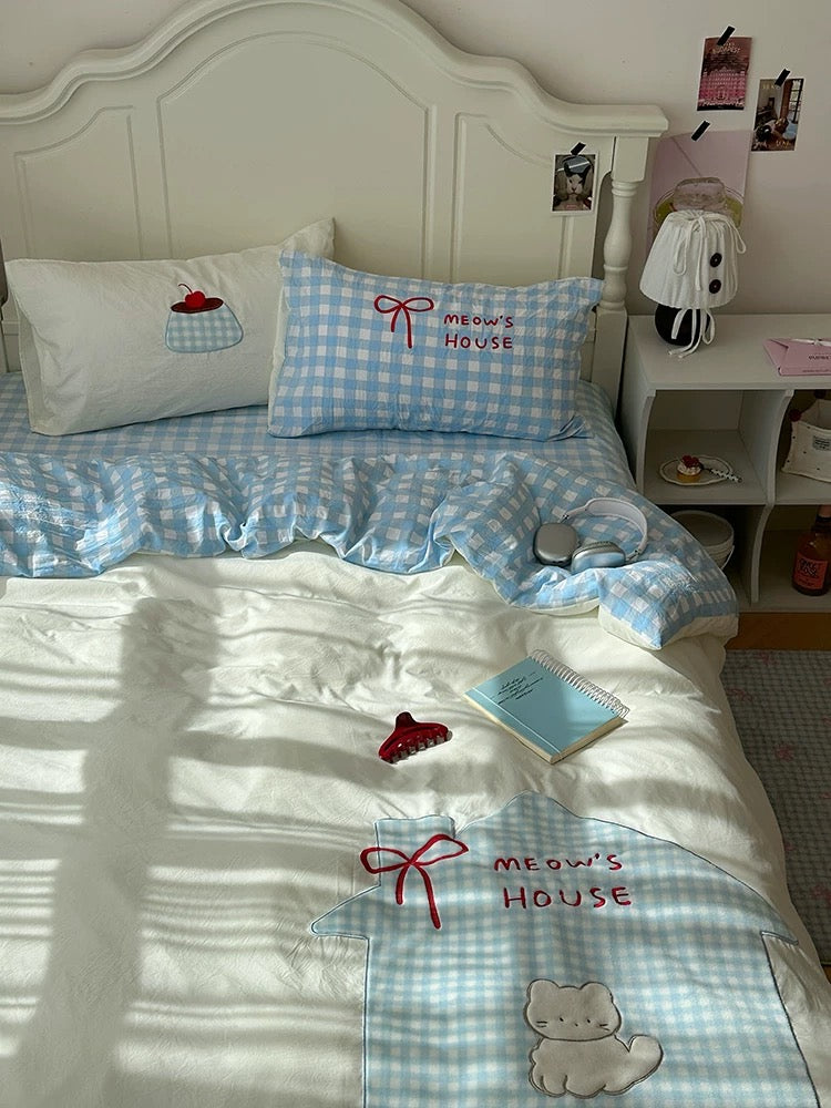 Embroidered cat quilt cover with soft pastel blue bedroom vibe.