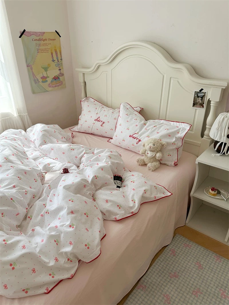 Bedroom with a bed featuring white bedding and pink accents, a teddy bear, and a nightstand.