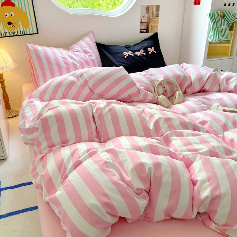 Pink striped cotton bedding set displayed on a neatly made bed in a pastel-themed room