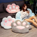Woman sitting on a paw-shaped cushion in a living room with other paw-shaped cushions.