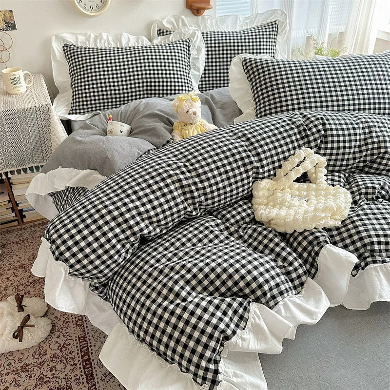 Bed with black and white checkered bedding and gray pillows in a bedroom setting.