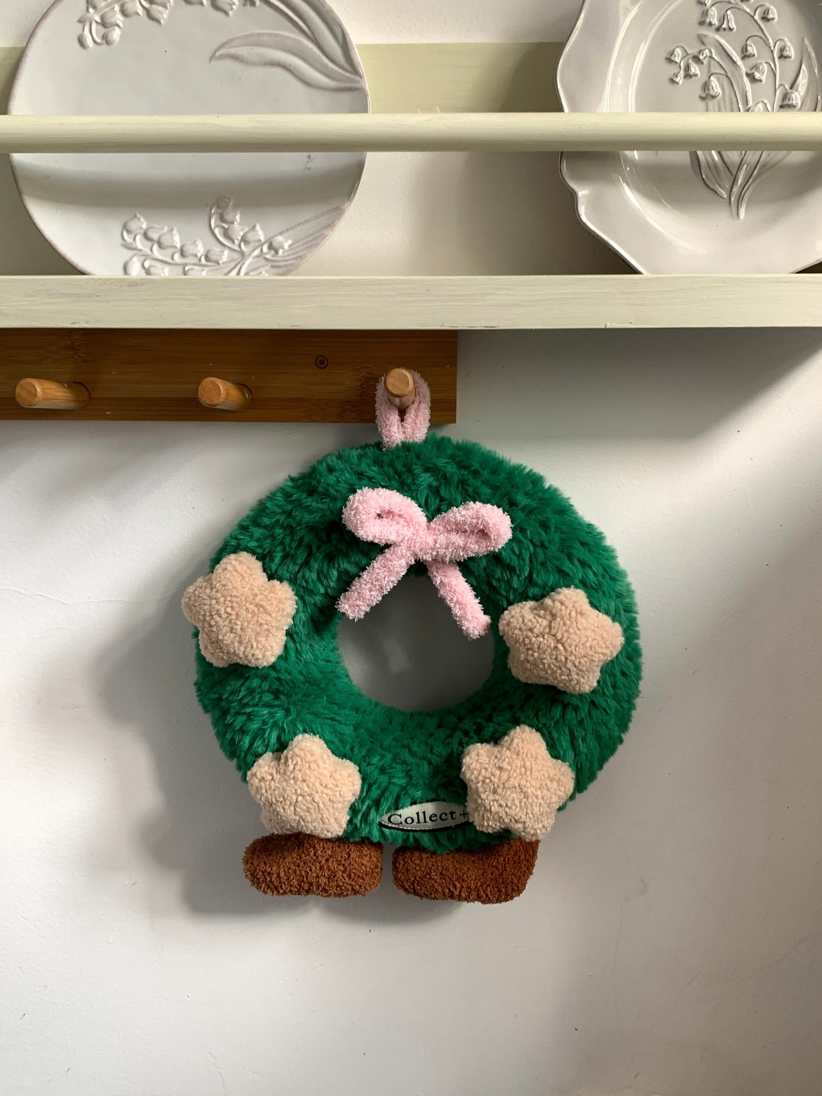Star decorated Christmas wreath cushion with pink bow and brown feet in a cozy room