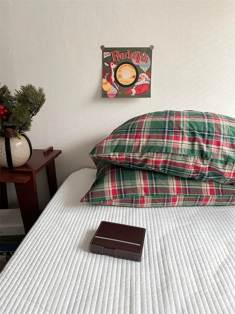 Stacked tartan pillowcases show green checks crossed by red and cream bands.