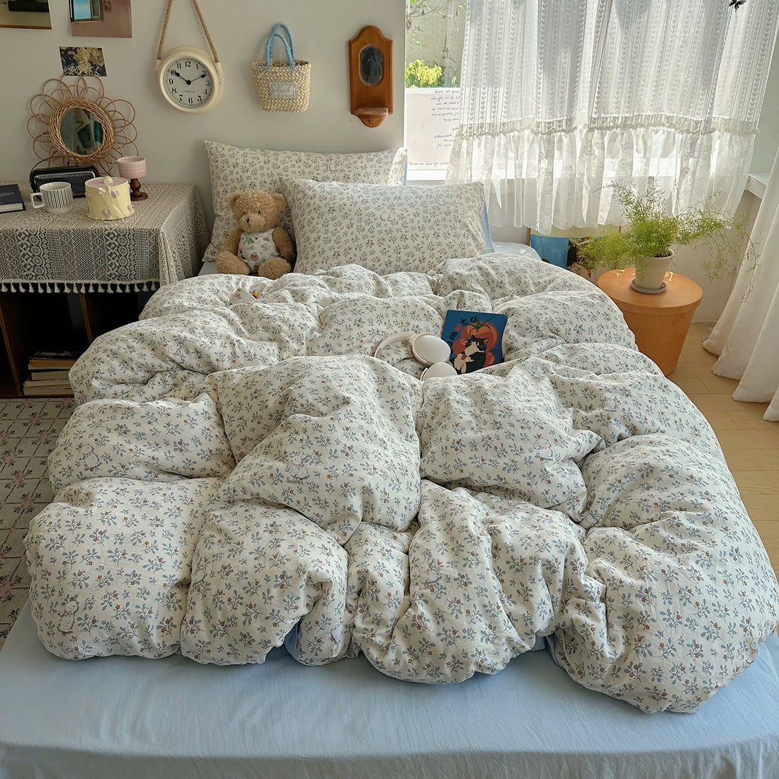 Floral patterned comforter on a bed in a bedroom with a teddy bear and decorative items.