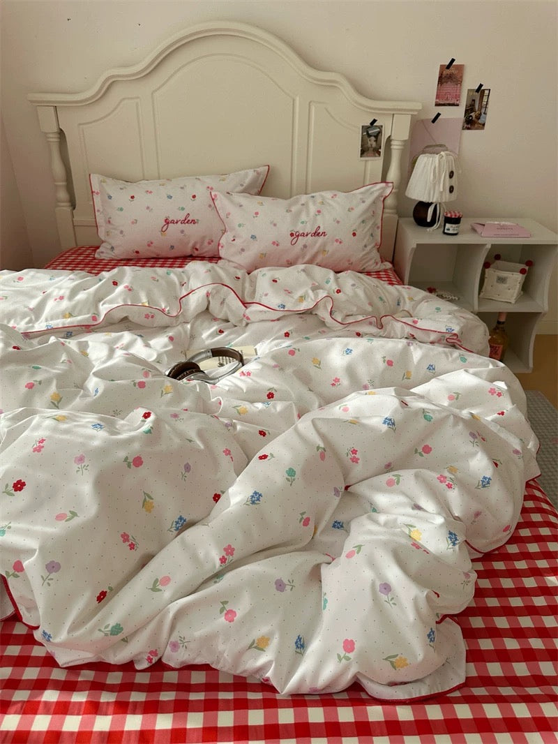 Floral patterned duvet cover on a bed with red checkered sheets, in a bedroom setting.