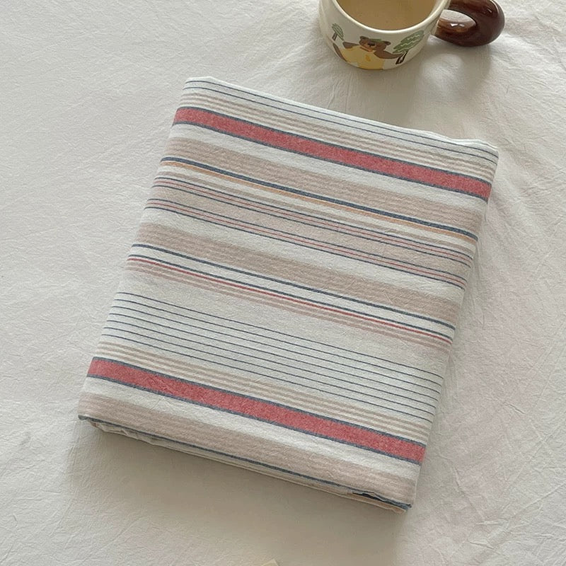 Folded striped fabric with a mug on a light surface