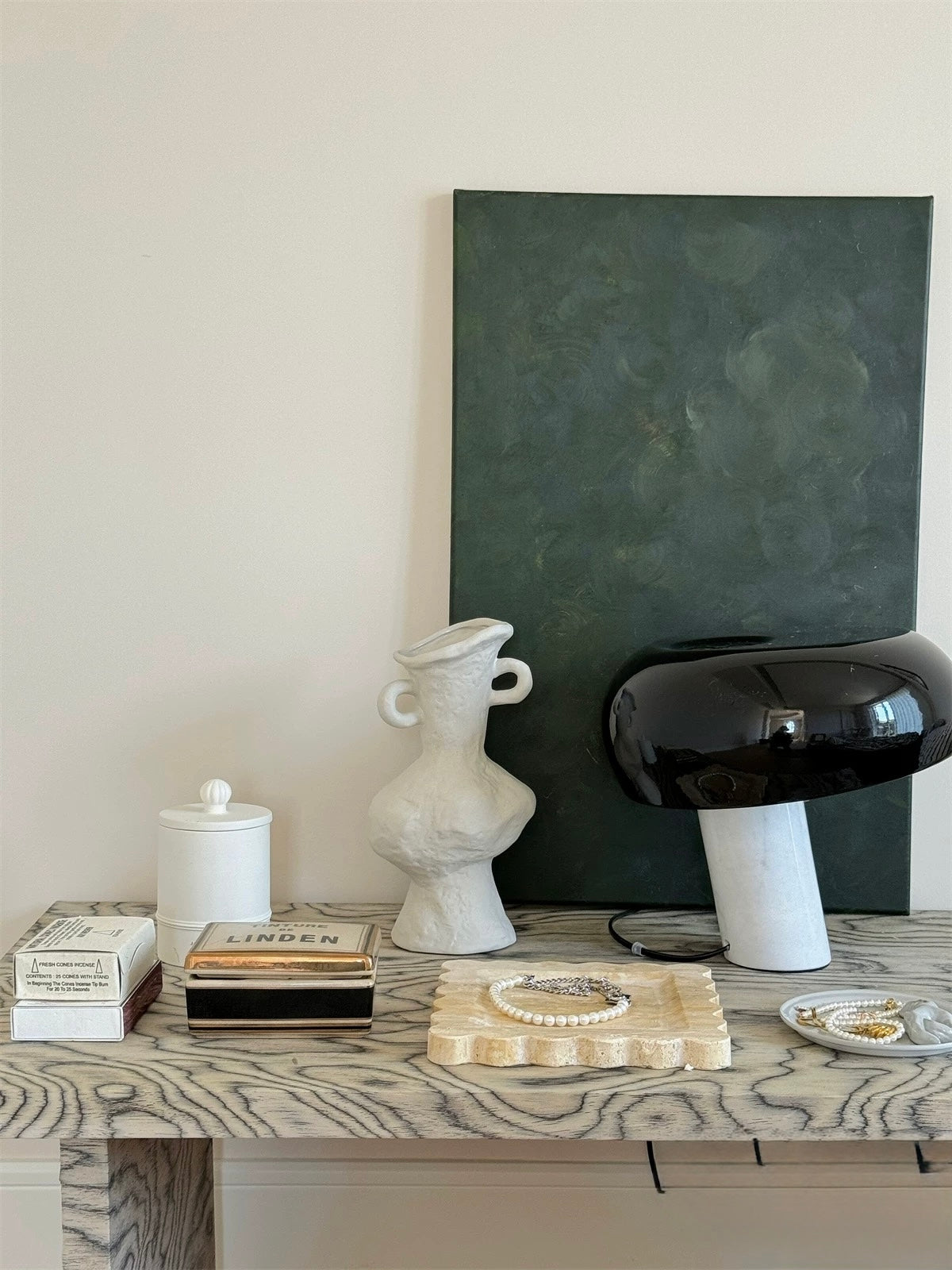 Decorative items on a wooden surface with a black abstract painting in the background.