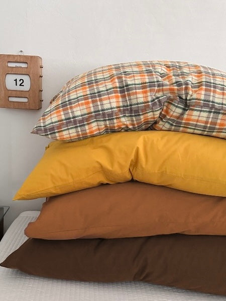 A plaid pillowcase tops a stack of mustard yellow, caramel and mocha designs.