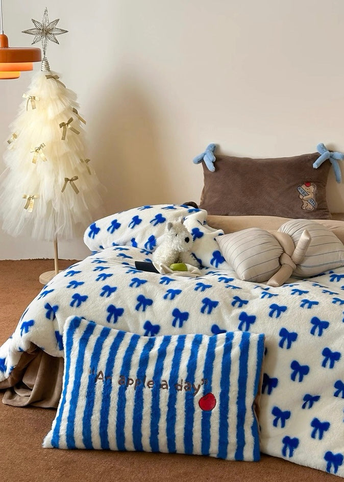 Bedroom with a bed covered in a white comforter with blue bows, striped pillow, and abstract painting on the wall.