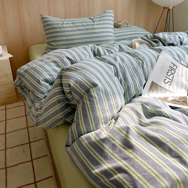 Striped bedding set on a bed with a wooden headboard and tiled floor.