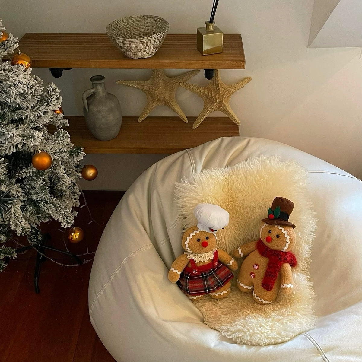 Whimsical Christmas decor includes a gingerbread man and woman on a chair beside a decorated tree.