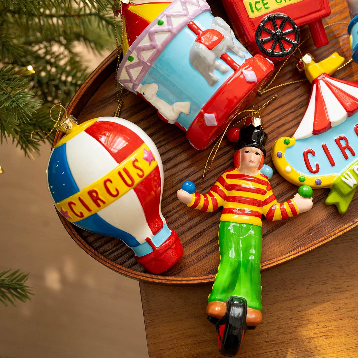 Whimsical Christmas ornaments show a clown, balloon and elephant carousel with bright circus details.