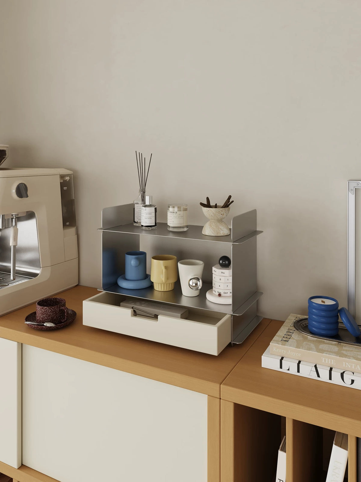 White two tier shelf with a drawer on a wood counter next to a coffee machine and a stack of books