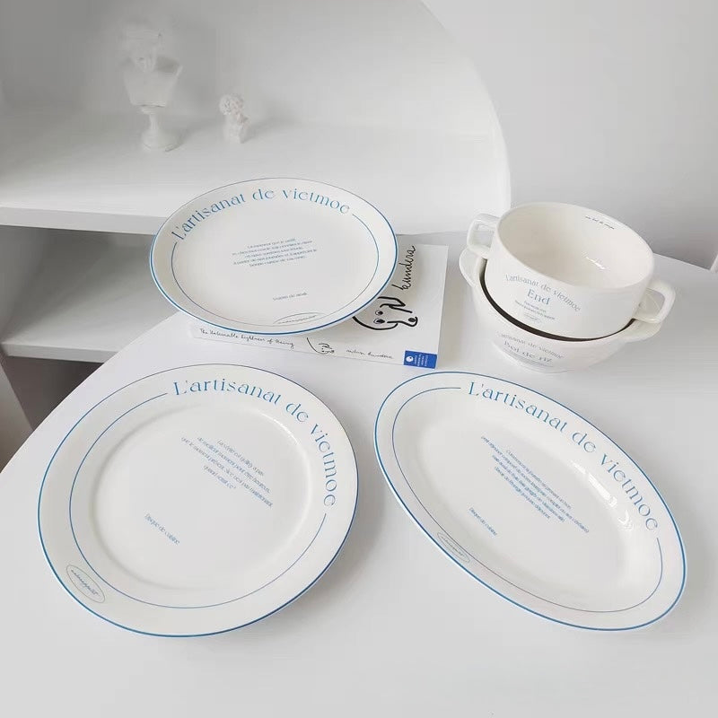 French bistro tableware including white plates bowls and handled dishes with fine blue printed typography