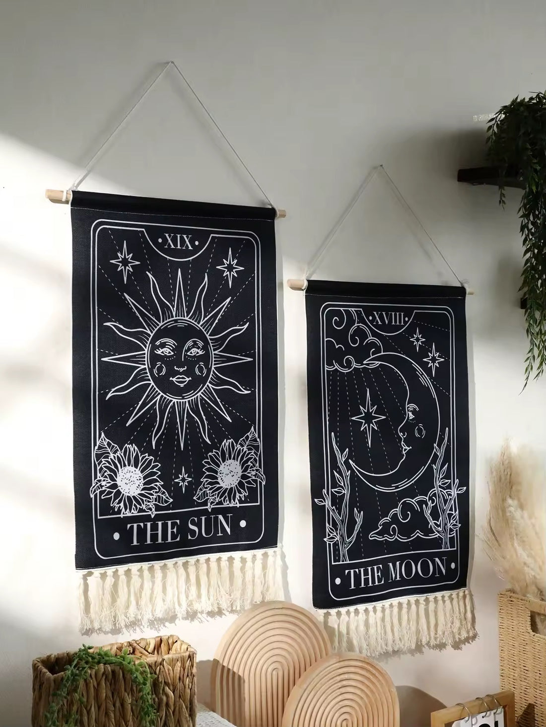The Sun and Moon hanging side by side on a minimalist white wall with plant accents.