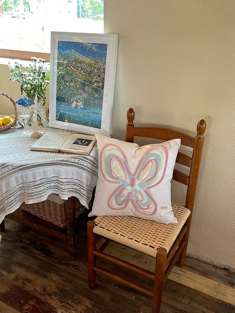 Y2K style pastel butterfly pillow on a wooden chair in a cozy reading corner