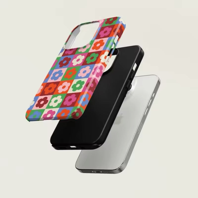 Close-up of the checkered flower iPhone case featuring bold retro grid design in red, green, pink, and blue