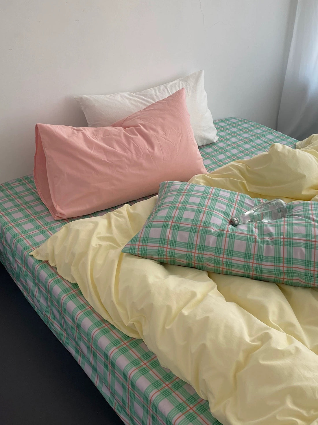 Bed with pink and green checkered bedding and pillows.