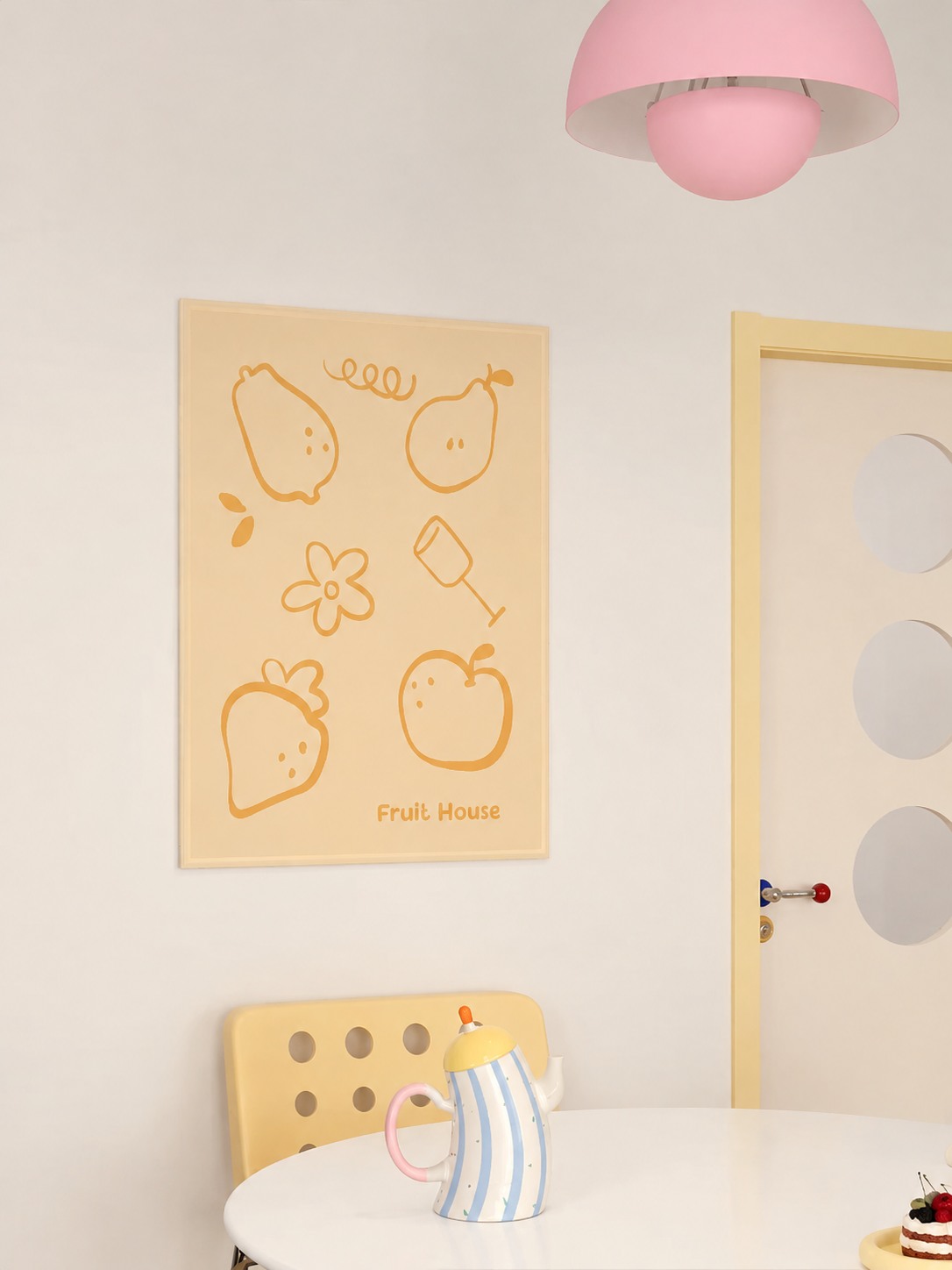 A yellow fruit wall hanging shows orange fruit outlines and a small flower above a yellow dining chair.