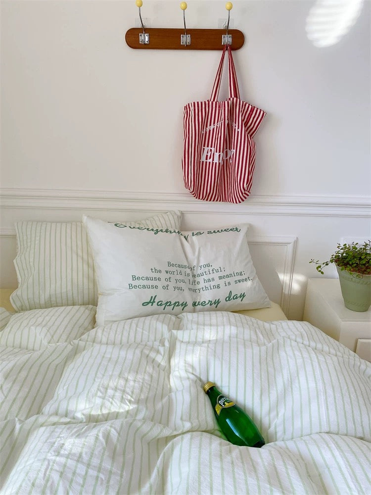 Bedroom with pillows and a bottle of champagne on a bed, red and white striped bag hanging above.