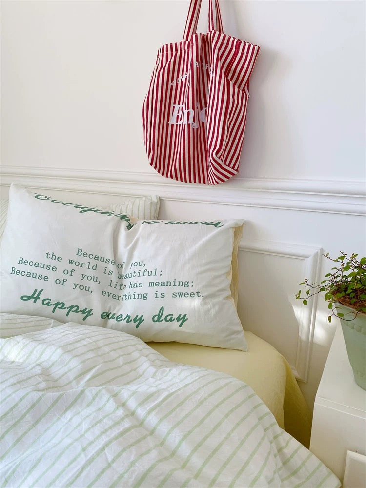Red and white striped bag hanging above a bed with motivational pillows.
