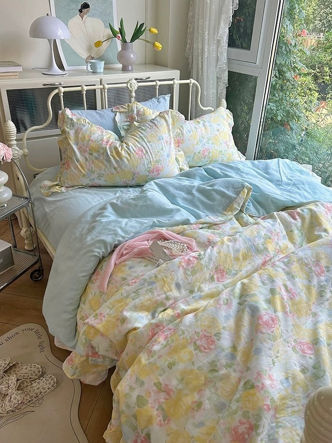 Yellow and pink watercolor rose bedding on a white vintage-style bed