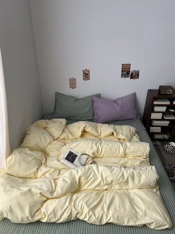 Yellow sage duvet cover set with lilac pillow and green striped bedding in a small bedroom